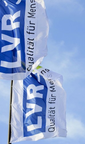 zwei Fahnen mit dem LVR-Logo vor blauem Himmel