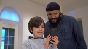 Vater mit Sohn, die auf ein Handy mit der Max Ernst App schauen.